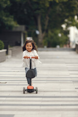 Obraz premium Child learn to ride scooter in a park on sunny summer day