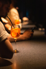 A glass of alcoholic cocktail with orange at the bar.