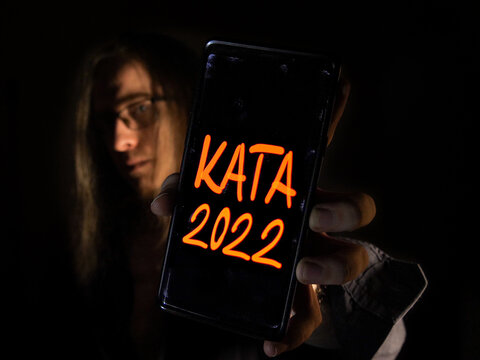 Business man shows the Kata Tax Law text on the mobile smart phone screen in isolated studio. Direct energy saving soft lighting and shadows background concept. 2022.07.18. Hungary, Budapest