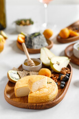 French and italian cheeses. Cheese and wine concept. Reblochon, Camembert, Caciotta, Langres on wooden plates with fruits and honey. Cheese plate, dish.