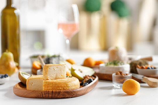 French and italian cheeses. Cheese and wine concept. Reblochon, Camembert, Caciotta, Langres on wooden plates with fruits and honey. Cheese plate, dish.