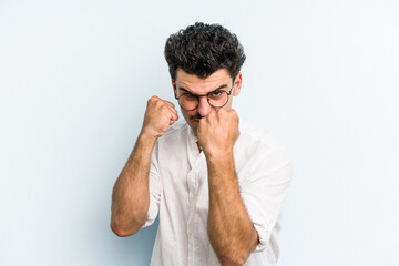 Young caucasian man isolated on blue background upset screaming with tense hands.