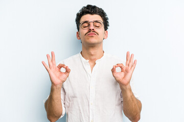 Fototapeta premium Young caucasian man isolated on blue background relaxes after hard working day, she is performing yoga.