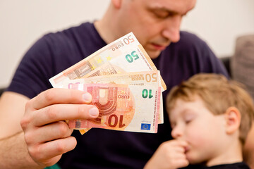 Mans and kids hands on Euro banknotes. Investment, children's life insurance, savings for...