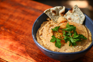 Close-up. Chickpea hummus dip with pita bread on a blue ceramic bowl, on wooden background with copy ad space for text