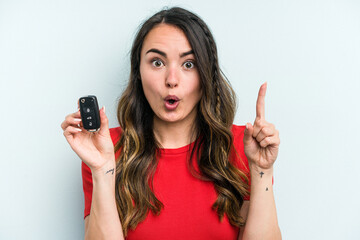 Young caucasian woman holding car keys isolated on blue background having some great idea, concept...