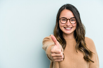 Young caucasian woman isolated on blue background smiling and raising thumb up