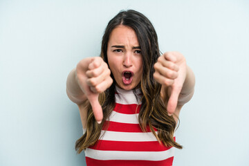 Young caucasian woman isolated on blue background showing thumb down and expressing dislike.