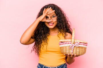 Young hispanic woman doing a picnic isolated on beige background excited keeping ok gesture on eye.