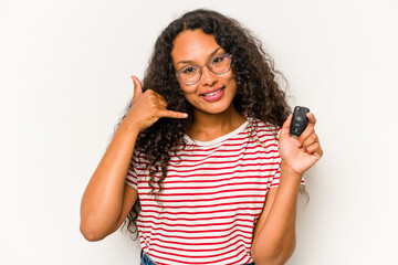 Young hispanic woman holding car keys isolated on white background showing a mobile phone call gesture with fingers.