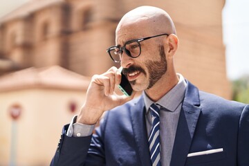 Young hispanic man executive talking on smartphone at street