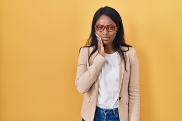 African young woman wearing glasses touching mouth with hand with painful expression because of toothache or dental illness on teeth. dentist