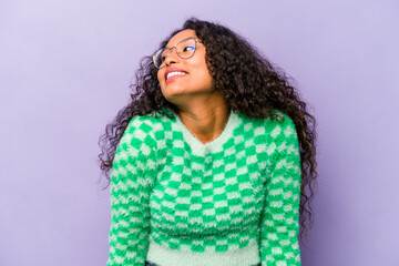 Young hispanic woman isolated on purple background laughs and closes eyes, feels relaxed and happy.