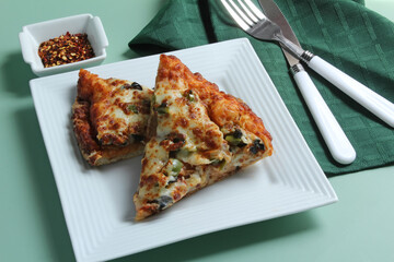 Pizza slices on a plate with chili peppers for an extra kick.