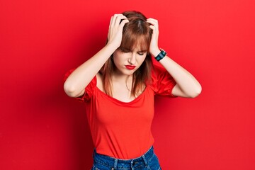 Redhead young woman wearing casual red t shirt suffering from headache desperate and stressed because pain and migraine. hands on head.