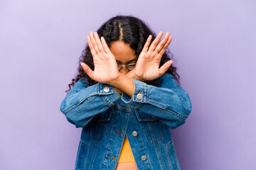 Young hispanic woman isolated on purple background keeping two arms crossed, denial concept.