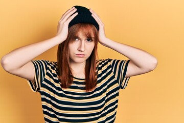 Redhead young woman wearing wool cap suffering from headache desperate and stressed because pain and migraine. hands on head.