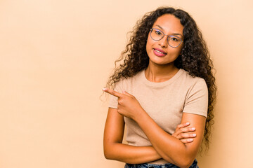 Young hispanic woman isolated on beige background smiling cheerfully pointing with forefinger away.