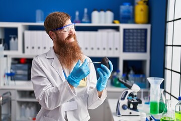 Young redhead man scientist injecting liquid on avocado at laboratory