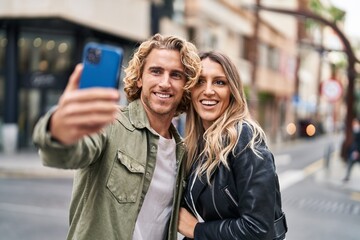 Man and woman couple smiling confident make selfie by the smartphone at street