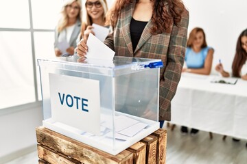 Group of young voter woman smiling happy putting vote in voting box at electoral center.