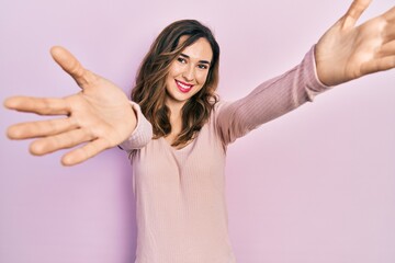 Young hispanic girl wearing casual clothes looking at the camera smiling with open arms for hug. cheerful expression embracing happiness.