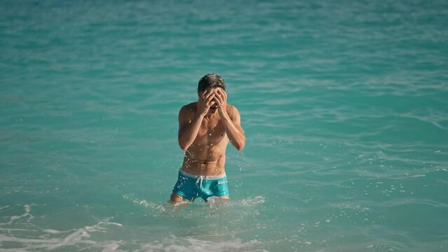 slow motion of muscular athletic man on beach in turquoise water of mediterranean sea in Oludeniz Beach in Aegean Sea after swimming. Summer tourist Season Fethiye, Mugla Turkey