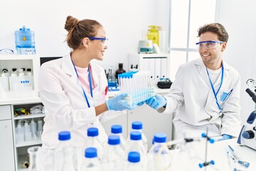 Man and woman wearing scientist uniform holding test tube at laboratory