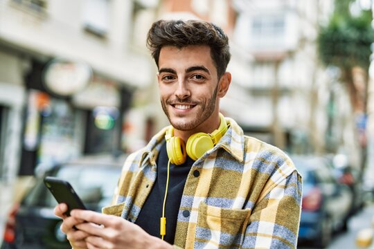 Handsome hispanic man smiling happy and confident at the city using smartphone