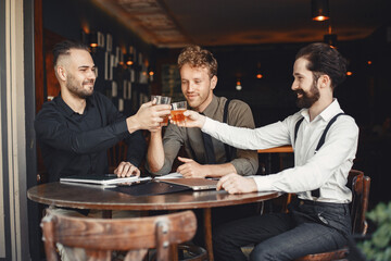 Three bearded men are drinking whiskey and talking.