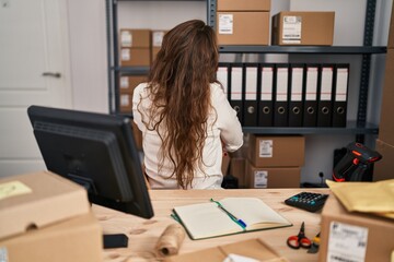 Young hispanic woman working at small business ecommerce standing backwards looking away with crossed arms