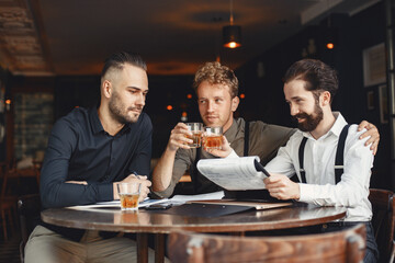 Three bearded men are drinking whiskey and talking.