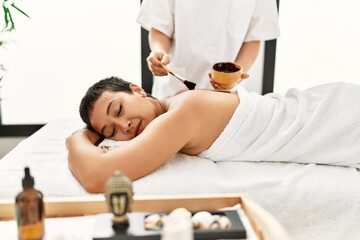 Obraz na płótnie Canvas Young hispanic woman having back skin treatment at beauty center