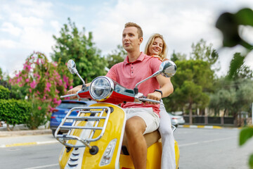 Fototapeta na wymiar Happy couple in love riding a motorbike on summer city streets ,man and woman travel . Young riders enjoying themselves on trip. Adventure and vacations concept.