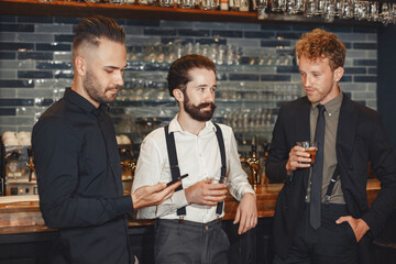 Three men are standing at the bar.