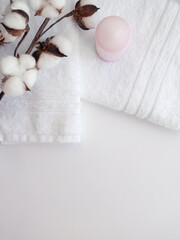 White towels with cotton flower branch and pink wax candle on the white background.