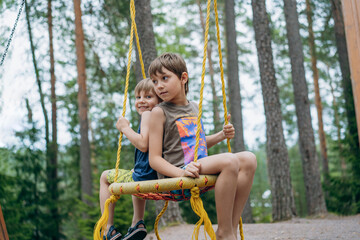 cute little boys having fun on a swing at playground