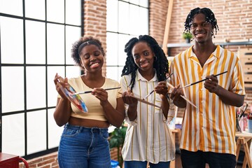 African american friends artists smiling confident holding paintbrushes at art studio