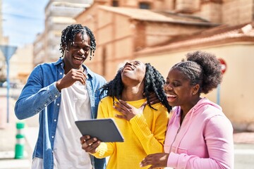 African american friends standing together watching video on touchpad at street