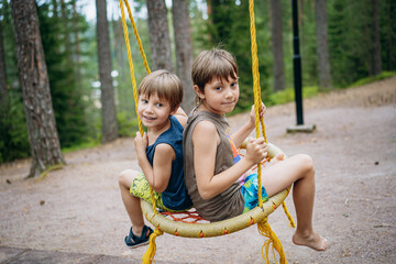 Fototapeta na wymiar cute little boys having fun on a swing at playground