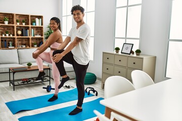 Fototapeta premium Young latin sporty couple smiling happy training at home.