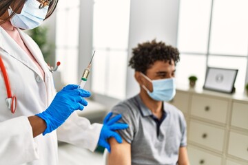 Naklejka premium Young doctor woman injecting covid-19 coronavirus vaccine for man.