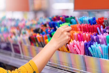 Close up hands choosing school stationery in the supermarket.