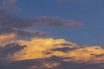 Obraz premium Golden and dark clouds on a sunset, dramatic evening blue sky background