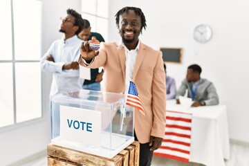 Young american voter man smiling happy holding i voted badge at electoral center.