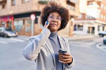 African american woman executive talking on smartphone drinking coffee at street