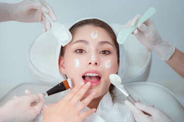 Naklejka premium Happy female face of young women who do cosmetic surgery and apply facial cream