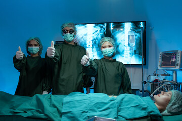 Confident team of surgeons in scrubs, caps and face masks standing with their arms folded and...