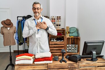 Middle age hispanic man working as manager at retail boutique smiling with hands on chest with closed eyes and grateful gesture on face. health concept.