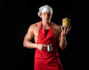 Sexy muscular man in chefs hat with sweet homemade stack of pancakes with syrup. Chef muscle man...